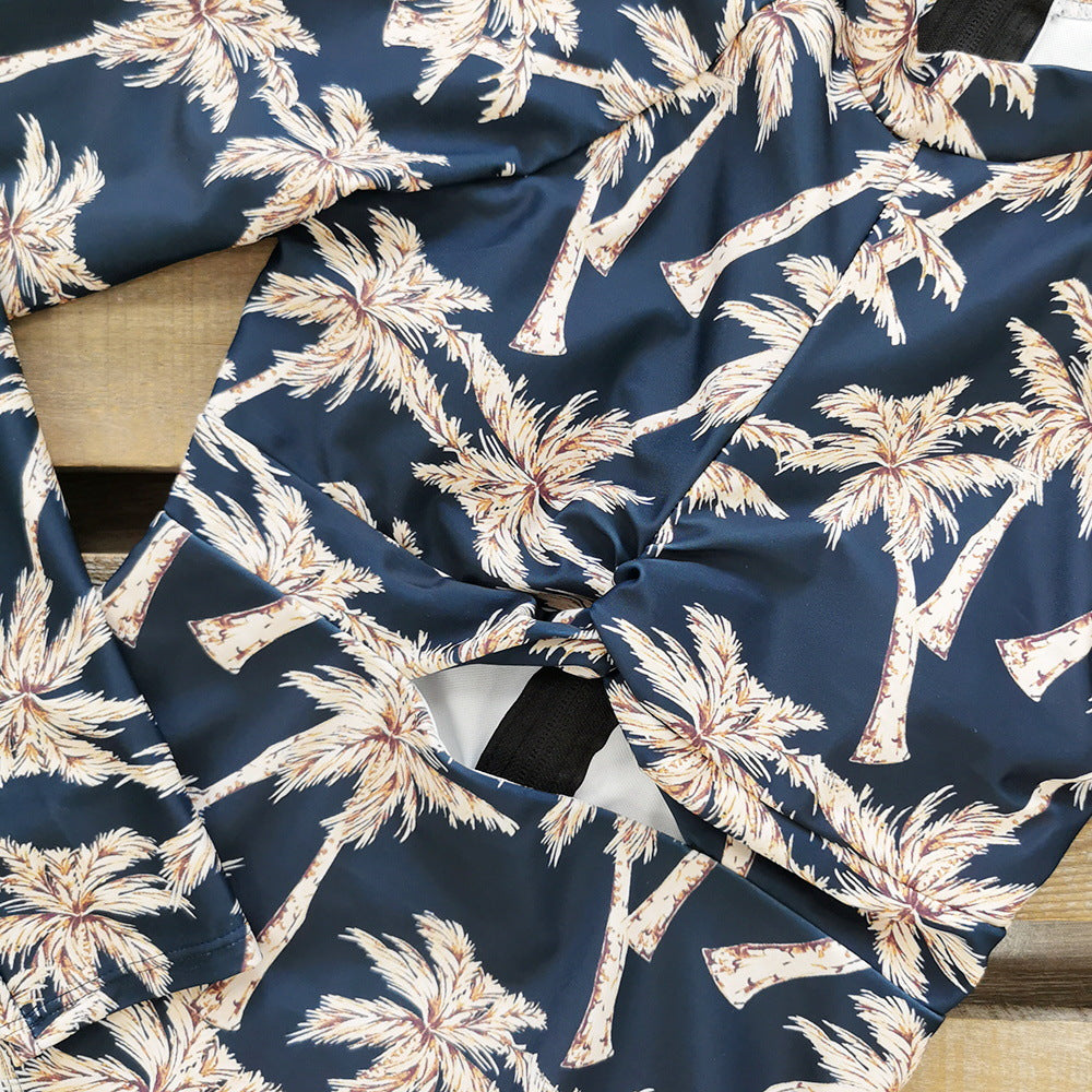 A long -sleeve,one-piece swimsuit with a blue and white palm leaf print and a zipper at the front