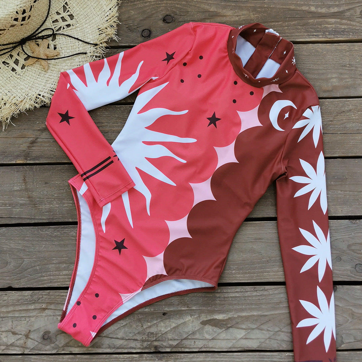 Vibrant pink and red long-sleeve swimsuit with bold sun and star patterns,perfect for a stylish beach look.