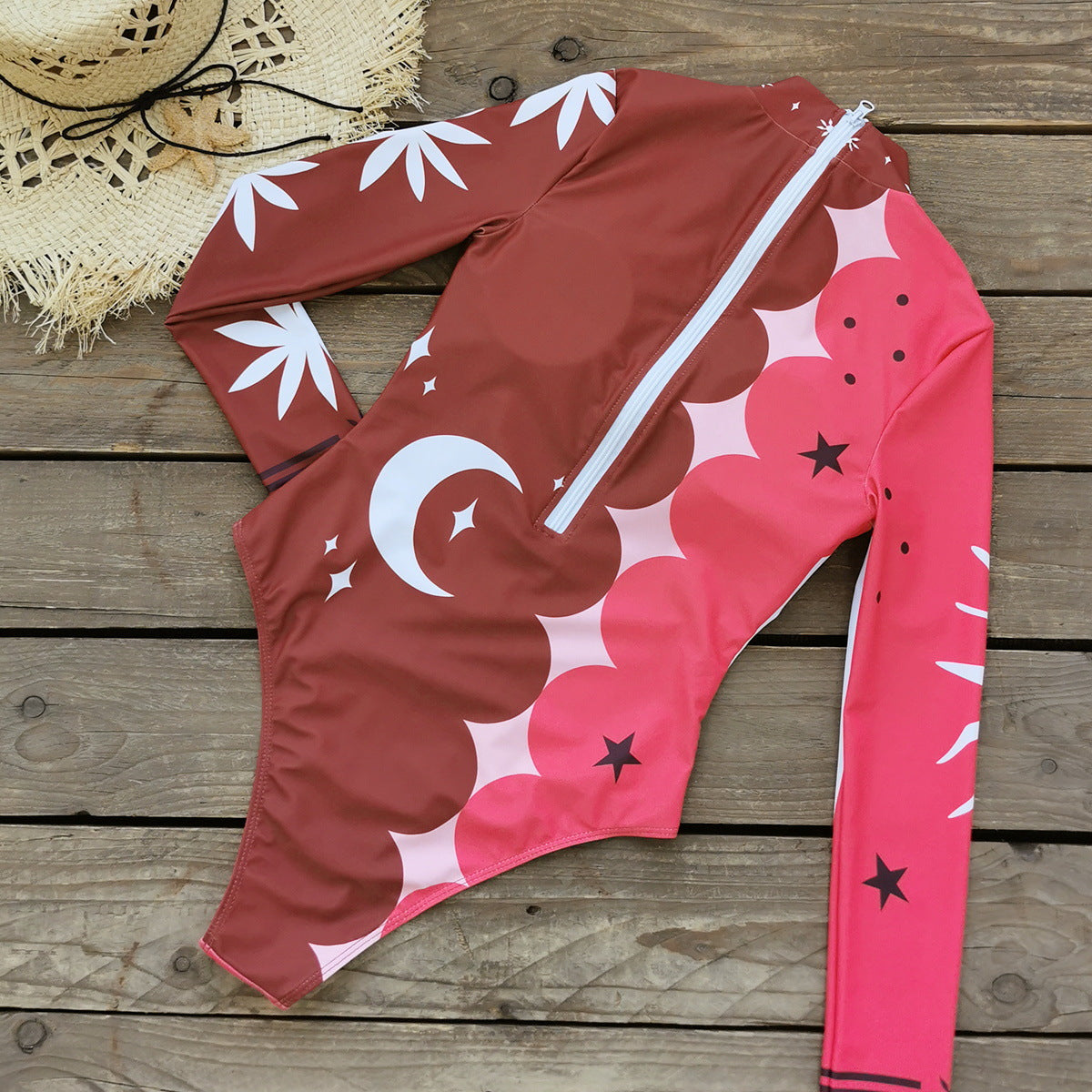 Vibrant pink and red long-sleeve swimsuit with bold sun and star patterns,perfect for a stylish beach look.