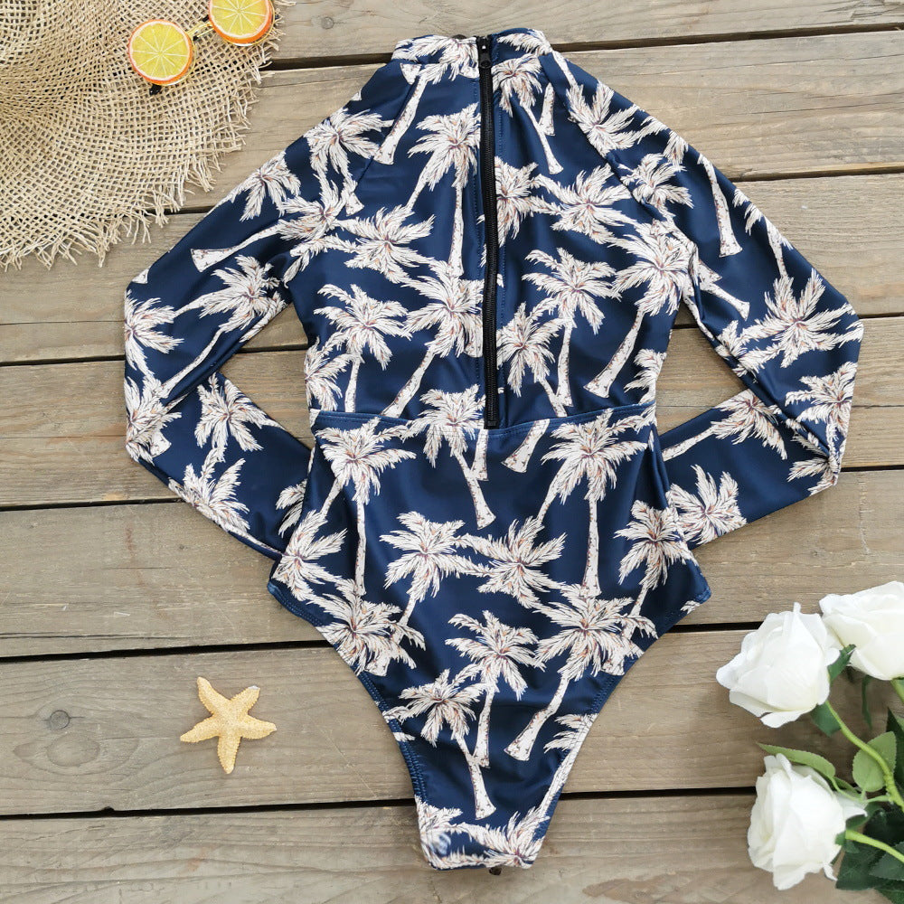 A long -sleeve,one-piece swimsuit with a blue and white palm leaf print and a zipper at the front