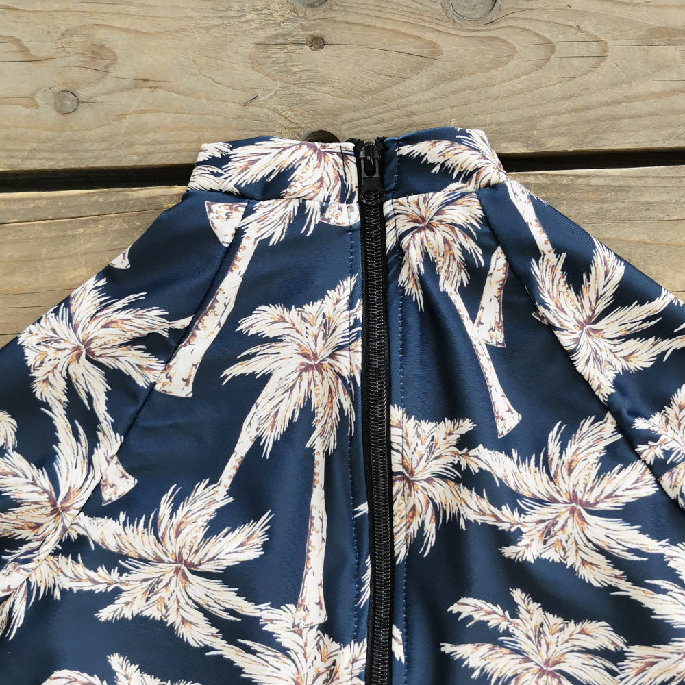 A long -sleeve,one-piece swimsuit with a blue and white palm leaf print and a zipper at the front