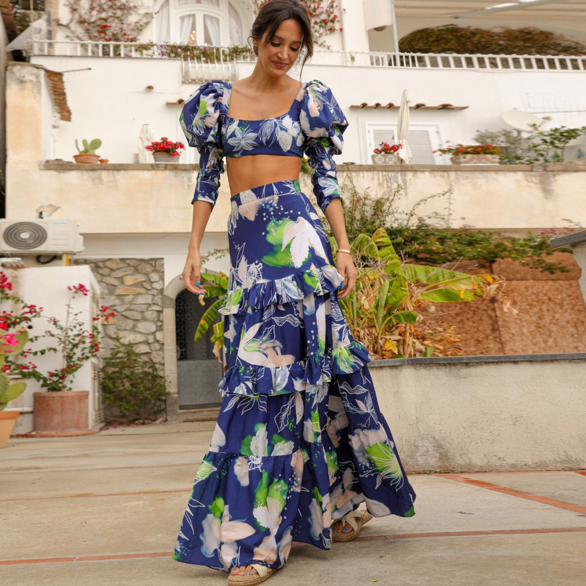 Stylish two-piece outfit consisting of a blue and white floral-print crop top with puff sleeves and a maching tiered maxi skirt.
