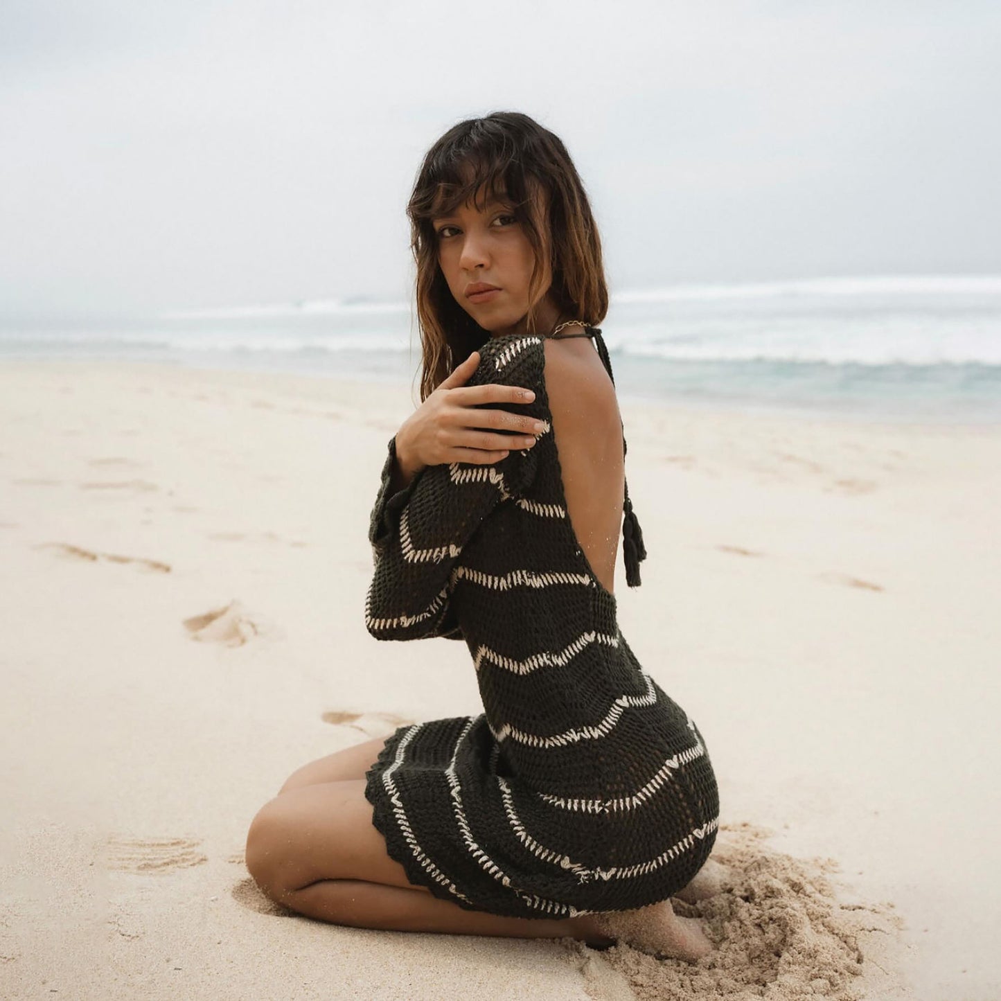 Lookin over her sholder while wearing a black and white striped top.