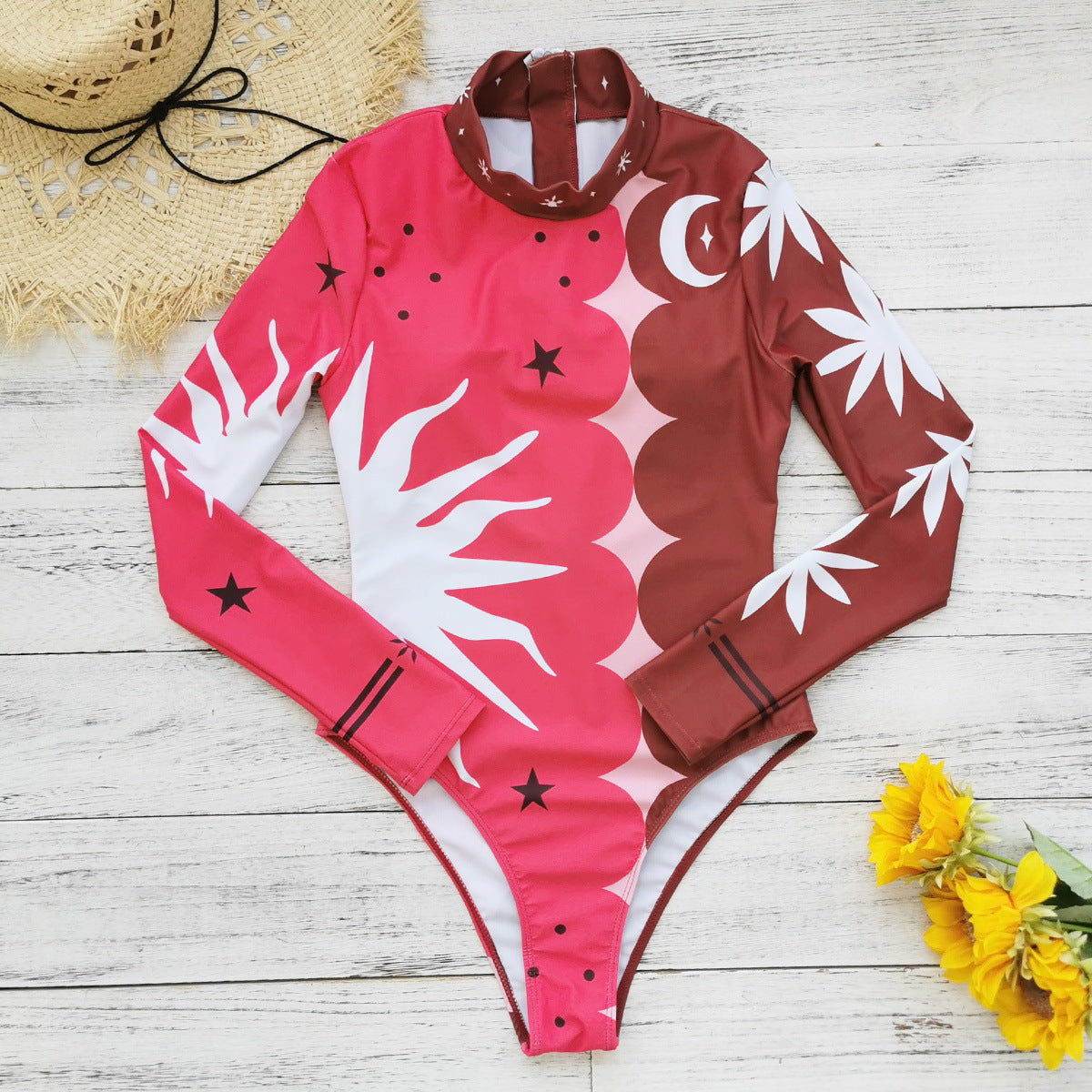 Vibrant pink and red long-sleeve swimsuit with bold sun and star patterns,perfect for a stylish beach look.