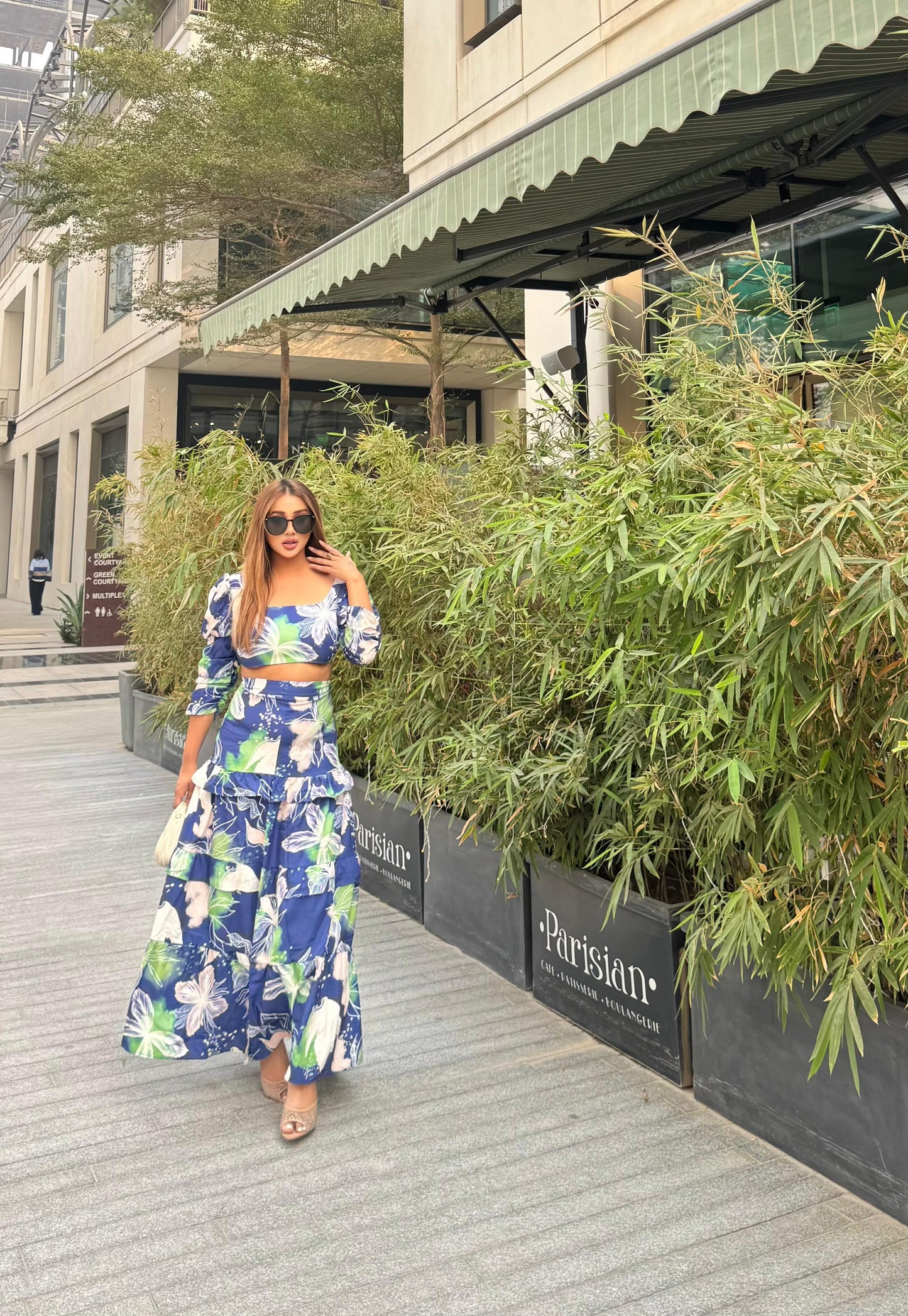 Stylish two-piece outfit consisting of a blue and white floral-print crop top with puff sleeves and a maching tiered maxi skirt.